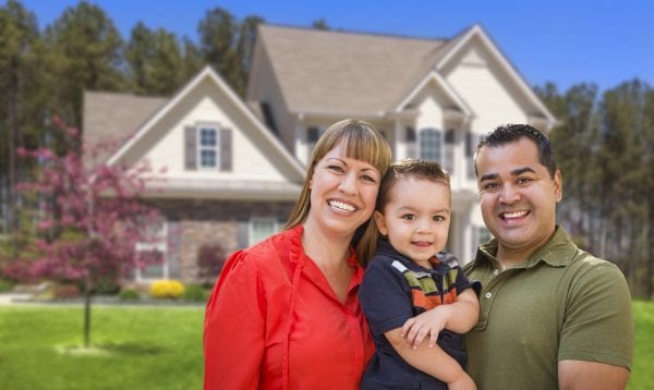Happy Mixed Race Young Family In Front Of Beautiful House.